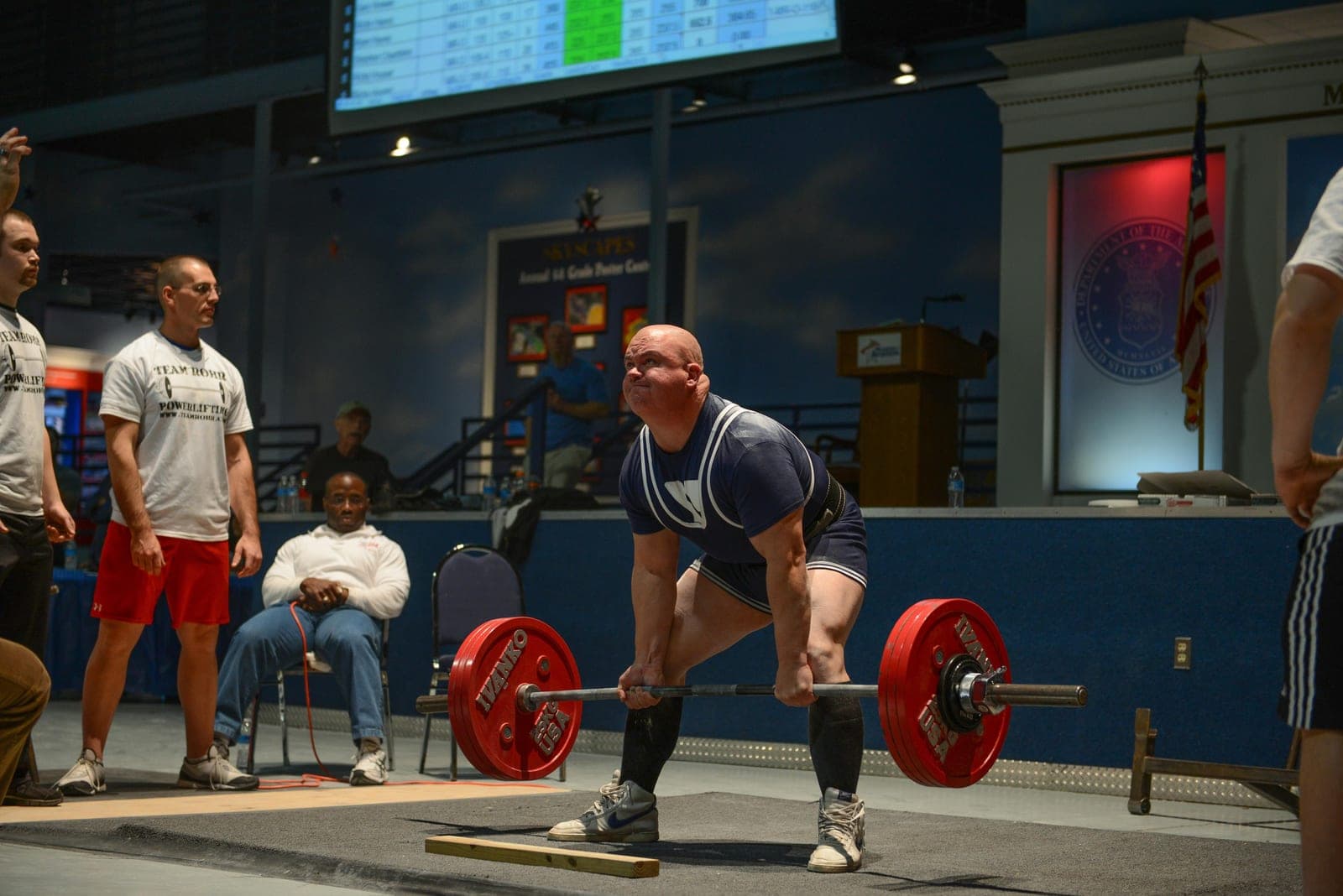 A powerlifter performs a deadlift with a loaded barbell during a competition.